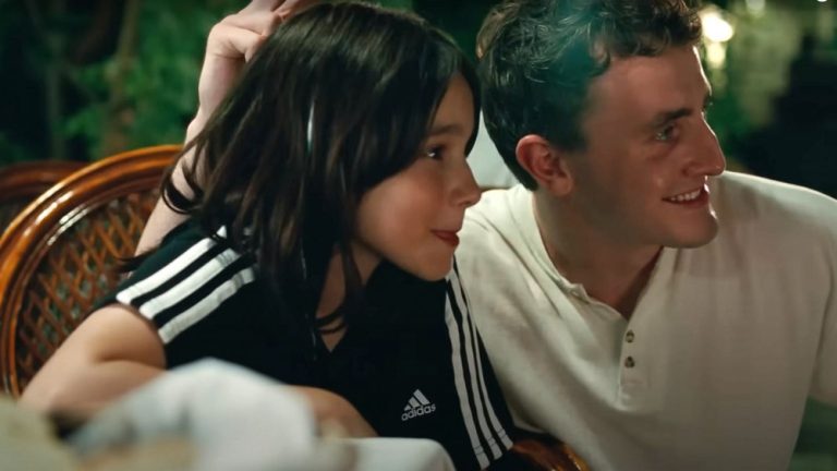 From "Aftersun," Sophie and her father pose for a photo while seated at a table