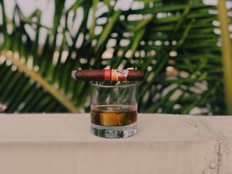 A cigar sitting on top of a glass of whiskey